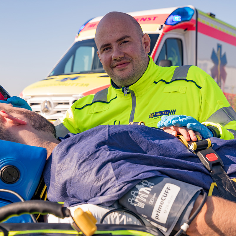 Notfallsanitäter der Veritas Ambulanz betreut einen Patienten auf der Trage vor dem Rettungswagen